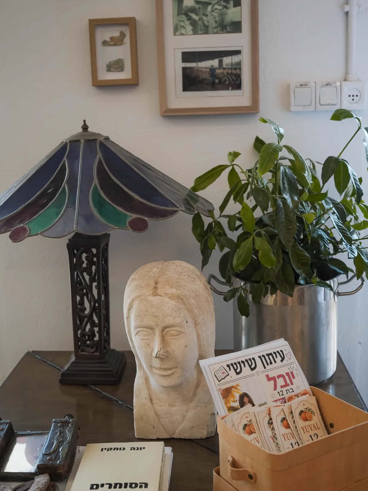 פריטים מעולמה של יונק'ה — פסל, מנורת ויטראז' ועיתון ישן