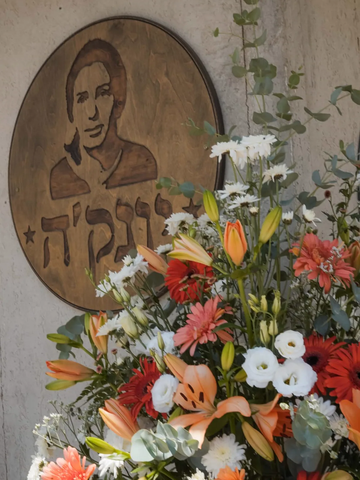 דיוקן עץ מגולף של יונה 'יונק'ה' נותקין, מעוטר בזר פרחים